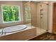 Modern bathroom with soaking tub and walk-in shower, accented by a large window overlooking greenery at 5103 Heathland Dr # 50, Charlotte, NC 28215