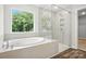 This bathroom features a modern shower, a soaking tub with a view, and stylish tile work at 5103 Heathland Dr # 50, Charlotte, NC 28215