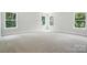 Bedroom with plush neutral carpeting and large windows offering view of the trees at 5103 Heathland Dr # 50, Charlotte, NC 28215