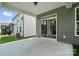 View of the concrete patio that leads to a sliding glass door, the backyard and a white house at 5103 Heathland Dr # 50, Charlotte, NC 28215