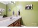 Half bathroom with vanity and mirror, featuring green walls with artwork at 534 Ballymote Ct, Matthews, NC 28104