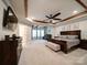 Luxurious main bedroom with a tray ceiling, ceiling fan, sitting area, and plush carpeting at 6004 Quintessa Dr, Matthews, NC 28104