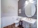 Stylish powder room with a wood accent wall, pedestal sink, round mirror, and hardwood flooring at 6004 Quintessa Dr, Matthews, NC 28104