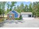 Charming blue home with stone accents, three-car garage and gravel driveway surrounded by lush trees at 720 Cricket Ln, Mt Ulla, NC 28125