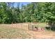 Fenced area of the property featuring a gate, wooded backdrop, and two cows relaxing in the sun at 720 Cricket Ln, Mt Ulla, NC 28125