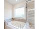 Bright bathroom showcasing a large soaking tub with tiled surround and a separate glass-enclosed shower at 8286 Ashvale Nw St, Concord, NC 28027
