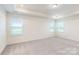 Bright bedroom with neutral carpet, tray ceiling, and natural light from three windows at 8286 Ashvale Nw St, Concord, NC 28027