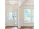 Bright foyer with wainscoting, light hardwood floors, transom window and decorative glass front door at 8286 Ashvale Nw St, Concord, NC 28027