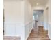 Bright hallway features wainscoting, hardwood floors, and views into adjacent rooms with a neutral color palette at 8286 Ashvale Nw St, Concord, NC 28027