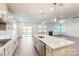 Kitchen with island bar, white cabinets, stainless appliances, hardwood floors, and views of the great room at 8286 Ashvale Nw St, Concord, NC 28027