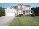 Lovely two-story house featuring a manicured lawn, attached garage, and welcoming covered front porch at 100 Oakwood Meadow Dr, Mooresville, NC 28115