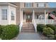 Inviting front porch with flowerpots, white railing, and brick stairs with well maintained garden at 100 Oakwood Meadow Dr, Mooresville, NC 28115