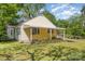 Exterior side view showcasing a covered porch with a ramp, situated on a grassy lawn with mature trees at 1302 N Ellis St, Salisbury, NC 28144