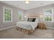 Bedroom featuring ample light from two large windows, a queen-size bed, and neutral decor at 13029 Whisper Creek Dr, Charlotte, NC 28277