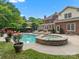 A backyard showcases a refreshing pool and an attached stone hot tub, with views of a brick home at 13029 Whisper Creek Dr, Charlotte, NC 28277