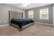 Main bedroom with a tufted headboard, carpeting, two windows, and neutral-toned walls at 131 Scotland Dr, Mooresville, NC 28115