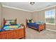 Bright bedroom with two beds, neutral walls, carpet flooring, window, and white trim throughout the room at 14837 Dungannon Ct, Charlotte, NC 28278