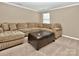 Bright living room featuring neutral walls, carpet, large sectional sofa, and a unique, leather ottoman at 14837 Dungannon Ct, Charlotte, NC 28278