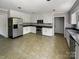 Well-lit kitchen with stainless steel appliances, white cabinets, and tile flooring at 1507 Chadmore Nw Ln, Concord, NC 28027