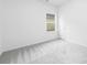 Empty carpeted bedroom with a large window, white walls, white door, and ample natural light at 220 S Columbia St, Gastonia, NC 28054
