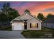 Charming single-story home featuring beige siding, a black roof, and an attached garage at sunset at 220 S Columbia St, Gastonia, NC 28054