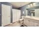 This bathroom offers a single sink vanity, framed mirror, shower with curtain and light wood flooring at 2215 Maycroft Dr, Charlotte, NC 28262