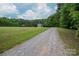 View of the house from the long gravel driveway, showing lawn and gazebo at 2609 Cove Creek Dr, Gastonia, NC 28056