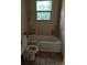 Bathroom features a bathtub and toilet beneath a window, with evidence of water damage at 2703 E Greenbriar Rd, Statesville, NC 28625