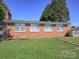 Expansive backyard features a lush lawn, mature trees, and a charming brick exterior with multiple windows at 303 Island Ford Rd, Maiden, NC 28650