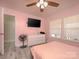 Pink bedroom with white accents, ceiling fan, gray wood-look flooring, and natural lighting at 303 Island Ford Rd, Maiden, NC 28650