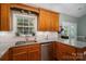 Well-lit kitchen with granite counters, stainless dishwasher, and wooden cabinets overlooking the backyard at 319 Beacon Hills Dr, Gastonia, NC 28056