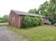 Rear exterior view of brick home with a covered area, grassy yard, and wooden deck with steps at 3750 Turner Rd, Clover, SC 29710