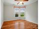 Bright bedroom featuring hardwood floors, a ceiling fan, and a view of the exterior landscape at 5028 Polo Gate Blvd, Charlotte, NC 28216
