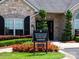 A brick building featuring a clubhouse sign, stone accents, manicured landscaping and trimmed trees at 5028 Polo Gate Blvd, Charlotte, NC 28216