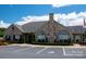 Stone clubhouse exterior featuring manicured landscaping, beautiful arched windows, and ample parking at 5028 Polo Gate Blvd, Charlotte, NC 28216
