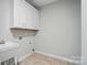 Simple laundry room with tile flooring, a utility sink, and white cabinets for storage at 5028 Polo Gate Blvd, Charlotte, NC 28216