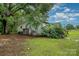 Side exterior view with lush landscaping, mature trees, shed/outbuilding, and wooden deck, creating a serene environment at 5240 Old Monroe Rd, Indian Trail, NC 28079