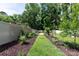 Backyard garden path features a wooden trellis on the white fence with lush greenery and landscaping at 5777 Stephanie St, Charlotte, NC 28212