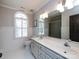 Bright bathroom features a double vanity with white cabinetry, tiled floor, and shuttered arch window at 5822 Alexa Rd, Charlotte, NC 28277