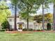 Charming painted brick home with mature trees in the front yard, complemented by manicured landscaping and a welcoming entrance at 5822 Alexa Rd, Charlotte, NC 28277