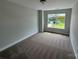 This bedroom has neutral carpeting, light grey walls, and a large window offering natural light at 6256 Culbert St # 187, Harrisburg, NC 28075