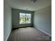 This bedroom has neutral carpeting, light grey walls, and a large window offering natural light at 6256 Culbert St # 187, Harrisburg, NC 28075