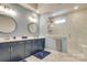Modern bathroom with double vanity, elegant lighting, and luxurious glass-enclosed shower with sleek white tile surround at 8221 Houser St, Cornelius, NC 28031