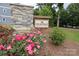 Community entrance with stone signage and lush landscaping featuring roses and greenery at 8221 Houser St, Cornelius, NC 28031