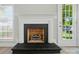 Close up of a black brick fireplace, with white trim and windows letting in plenty of natural light at 8309 Emily Dr, Harrisburg, NC 28075