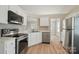 Bright kitchen featuring stainless steel appliances, white cabinets, and an adjacent dining area at 8309 Emily Dr, Harrisburg, NC 28075