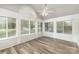 The sunroom has gray laminate flooring, a ceiling fan, and many windows that let in natural light at 9013 Trellis Pointe Blvd, Charlotte, NC 28227