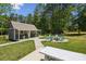 Charming backyard featuring a quaint cottage, outdoor fire pit, and green Adirondack chairs perfect for relaxation at 9115 Providence S Rd, Waxhaw, NC 28173