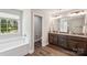 Bathroom showcases a dual-sink vanity, dark wood cabinets, a tiled backsplash, and a garden bathtub at 9115 Providence S Rd, Waxhaw, NC 28173