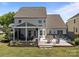 Inviting back patio boasts a hot tub, fire pit, and screened-in porch with outdoor seating under cafe-style lights at 9871 Travertine Trl, Davidson, NC 28036